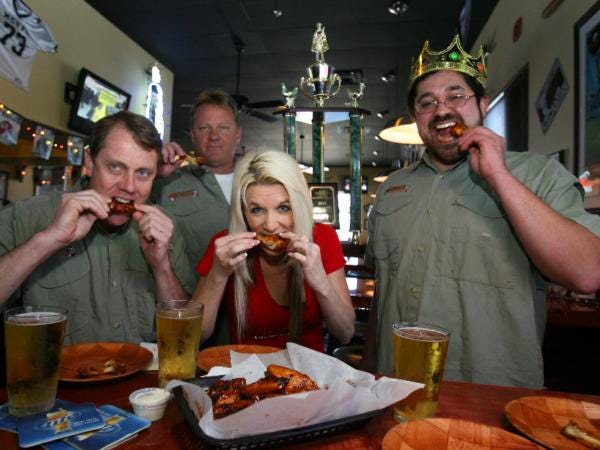 Co-owners Dan and Dennis Henderson, left, eat some of their signature "MVP" wings with Rhonda Dixon, the manager, and Joshua Moreno, the general manager, right, at The Dugout on Southeast Maricamp Road in Silver Springs Shores. The sports bar and grill recently won The King of the Wing award.