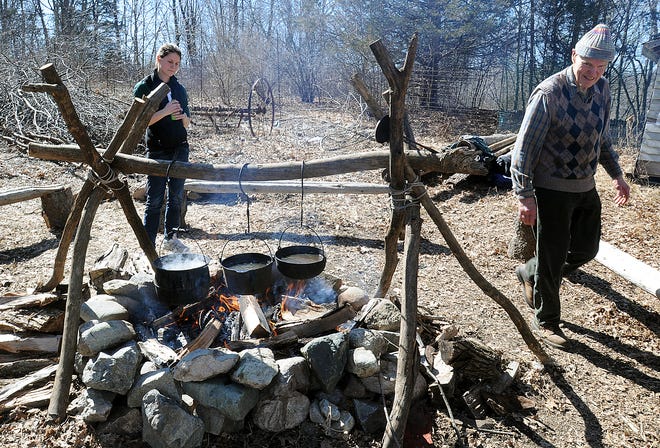 Leslye Penticoff and Charlie Williams demonstrate the colonial style of maple sugaring during the Natick Community Organic Farm annual Maple Magic Day yesterday in Natick.