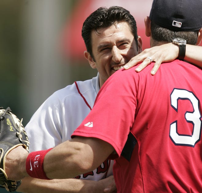 Former Red Sox shortstop Nomar Garciaparra (left) hugs Boston catcher Jason Varitek after Garciaparra threw out the ceremonial first pitch before yesterday's preseason game. Garciaparra signed a one-day contract with Boston so he could retire a Red Sox.