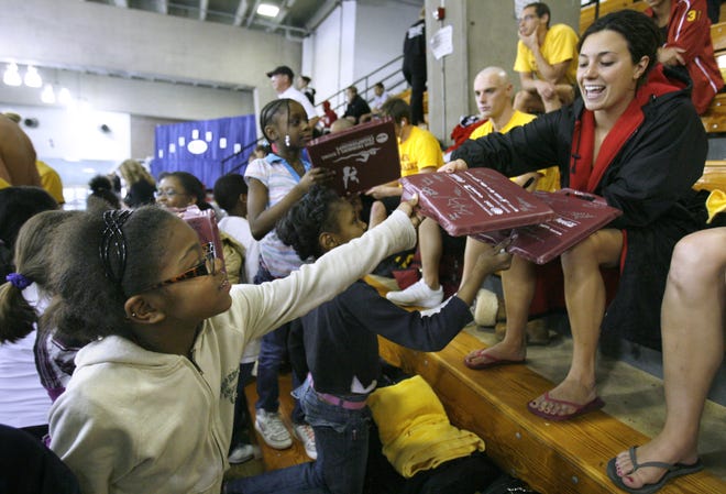 Gibbs Elementary School third-grader Shaneia Blile (left) hands a seat cushion for University of Tampa swimmer Ellie Eschleman to autograph during Wednesday’s NCAA Division II Swimming and Diving Championships at C.T. Branin Natatorium.