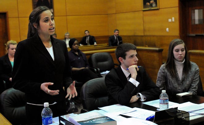 Milford High School student Elizabeth Fernandes, left, delivers her opening arguments as co-counsel Patrick Bedard and Leah Beaudoin look on during a mock trial competition against the Windsor School of Boston at Framingham District Court yesterday. Milford was competing as a Sweet 16 regional finalist in the 25th annual Mock Trial Program.  Windsor won the match to eliminate Milford and advance to the next round. The program is organized by the Massachusetts Bar Association.
