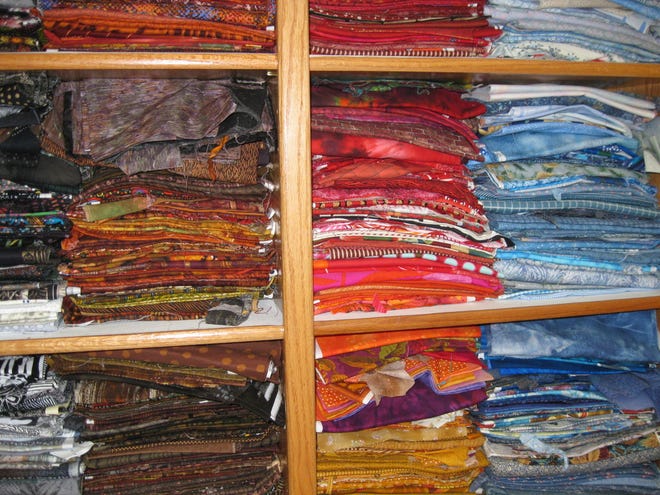 Fabric on shelves in Powers' studio/office are sorted by color and design, such as batik or novelty prints.