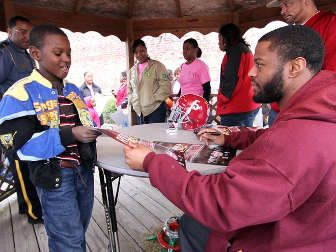 Former Alabama football star Roy Upchurch signs an autograph for Lamonte Shaw, 9, during a youth rally and parade in Greensboro on Saturday. Upchurch, former running back for the Tide’s national championship team, was the guest speaker and grand marshal of the rally presented by the Beauties of Distinction Social Saving Club.