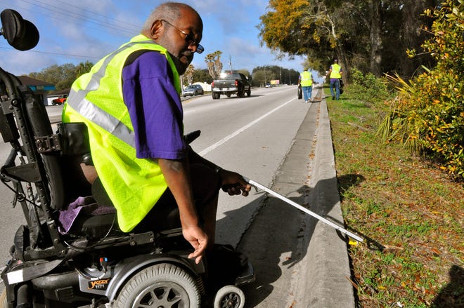 Louis Addison and other members of the Psi Chi Chapter of Omega Psi Phi, work together to pick up roadside trash Saturday along their adopted stretch of County Road 484 in Marion County.