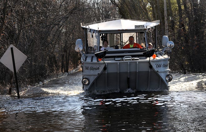 A Boston Duck Tour amphibious vehicle, with "Jailbird" George Kilroy at the helm, plows down Pelham Island Road in Wayland on the second day of service for residents of the Pelham Island Road area on Wednesday afternoon.