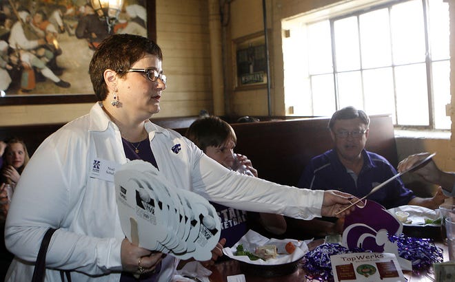 Noel Schulz passes out Frank Martin masks Thursday at the Kansas State Alumni Party at TapWerks in Oklahoma City. Schulz is the wife of Kansas State University president Kirk Schulz.