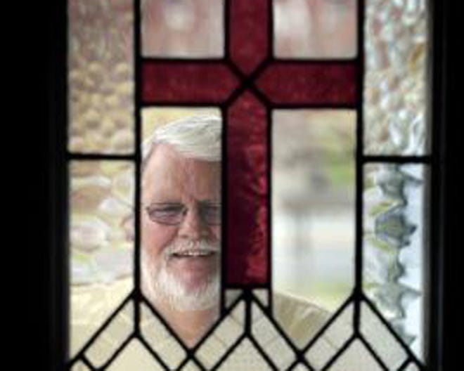 Barry Forde looks through a stained glass window at his south Augusta home. He and his family moved to Augusta's Alleluia Community in the early 1980s.