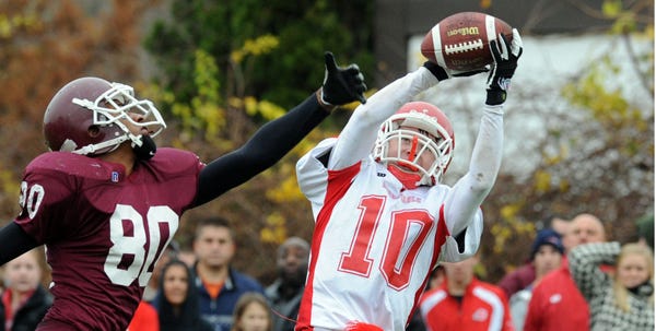 Barnstable's Matt Delaney makes a catch over the head of Falmouth's DK Johnson on Thanksgiving Day 2009. Athletic programs from across the state will vote Friday on whether to change the current football playoff system.