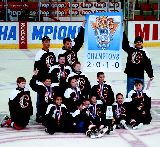 The Cheboygan Vapor pose with championship banner and trophy on the ice at Joe Louis Arena.