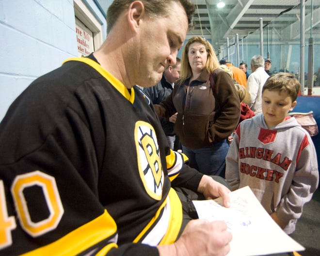 Bruin #40 Bruce Shoebottom signs a souvenir Bruins book for Mike Carroll of Hingham.