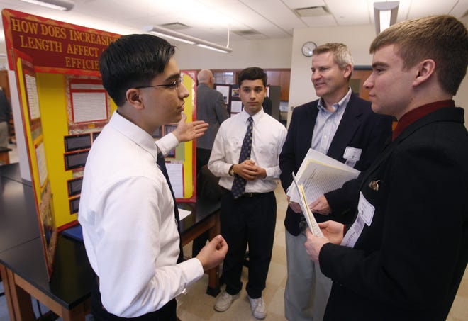 St. Paul Elementary School students, Krish (left) and Karan Dewan (second from left) speak with judges Joe Kolp (third from left) and Brock Witting about their science fair project, “How Does Increasing the Cord Length Affect Propeller’s Efficiency?” during the Ohio District 13 Science Day at Mount Union College Saturday.