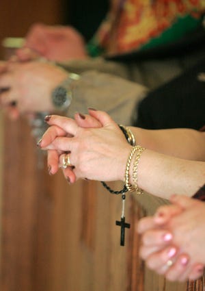 Hands clasp in prayer inside St. Andrew the Apostle Church.