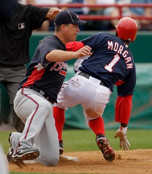 Washington Nationals' Nyjer Morgan (1) beats the tag by Atlanta Braves third baseman Chipper Jones, left, to steal third base during the fourth inning of a spring training baseball game Sunday, March 28, 2010 in Viera, Fla. (AP Photo/Charlie Riedel)