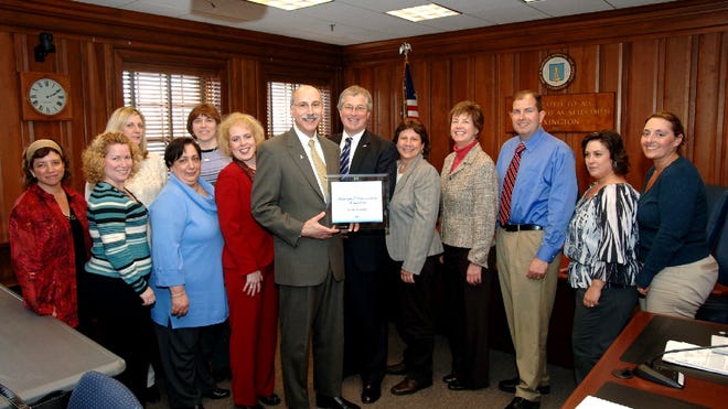 John Coughlin, vice president of select markets at Blue Cross Blue Shield of Massachusetts (BCBSMA), presents the Municipal Blue Innovation Award to Lexington Town Manager Carl Valente. Pictured, from left: Lexington Wellness Committee members Lori Kaufman, Michelle Malone, Lori Manning, Sandy Hart and Dianne Snell; Lexington Human Resources Director Denise Casey; Valente; Coughlin; Karen Simmons, Wellness Committee; Suzanne Donahue, BCBSMA account executive; Lexington Health Director Gerard Cody; Robin Vella, Wellness Committee; and Lisa Rozzi, Wellness Committee.