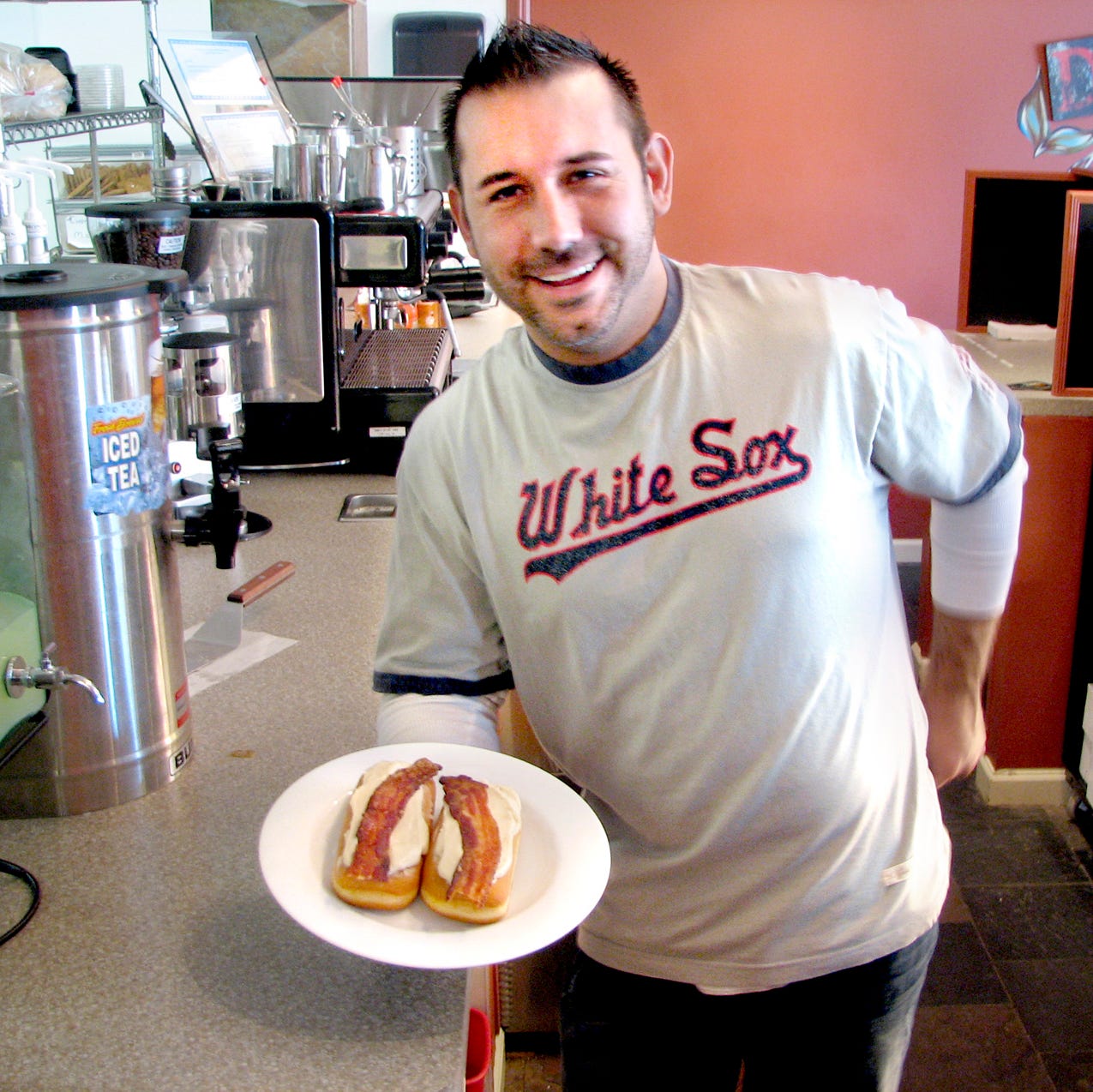 Travis Mohlenbrink, owner of Cracked Pepper Catering and Bakery, pauses with a tray of fresh Bacon Logs. The unique pastry gets a lot of attention from newcomers to the eatery. He says men think it's a great idea, while women tend to back off.