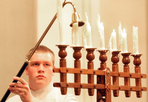 Matthew Taylor, acolyte, extinguishes the fourth of seven candles during Good Friday Services at Trinity Lutheran Church in Galesburg. The program was part of Community Holy Week.