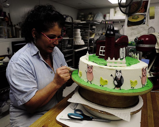 Marlene Souza, owner of Molly B Cakes of Distinction & Design, prepares a three-tiered, farm-themed cake at her Berkley site.