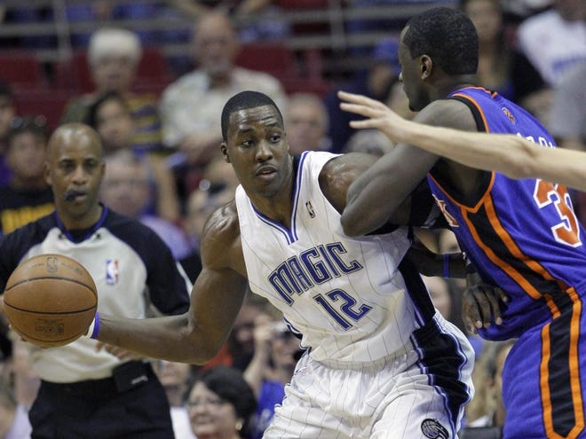 Orlando Magic center Dwight Howard (12) passes the ball to a teammate as he is guarded by New York Knicks forward Earl Barron during the first half in Orlando on Friday.