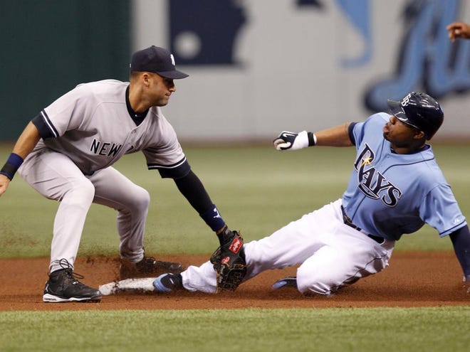 The Rays' Carl Crawford, right, slides in safely with a steal ahead of the 
tag by Yankees shortstop Derek Jeter, left, during the first inning Sunday 
in St. Petersburg.