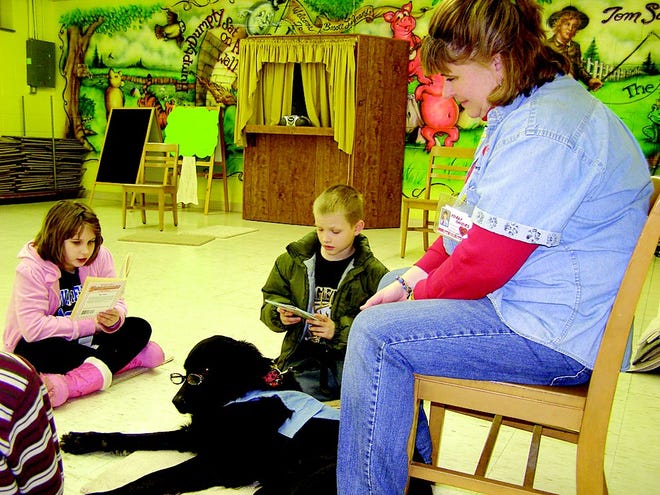 Olivia Betts, 9, reads to Piper while Josiah Fisler, 10, waits his turn. Owner Roxanne Davenport, herself a teacher, sets aside her instructional skills and simply listens as well.