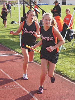 Sturgis’ Alex Keyser (back) hands off the baton to sister Kelsey Keyser in the 3,200-meter relay Tuesday.