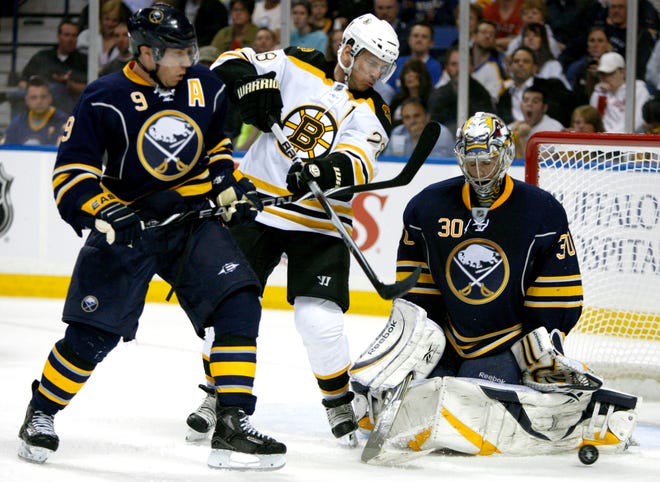 Buffalo Sabres goalie Ryan Miller stops a shot as teammate Derek Roy, left, tries to clear out Boston's Mark Recchi.