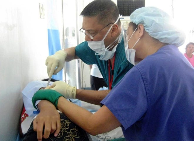 Alfredo Iloreta and his wife, Maria, work on a patient during a medical mission to the Phillipines in 2009. A trip in February included about 40 people, including physicians and nurses.