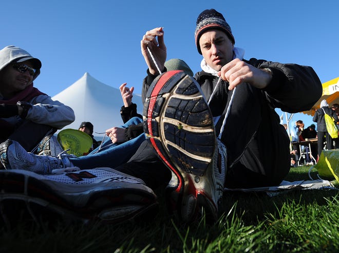 Devin O'Reilly of Wellesley ties his sneakers before the race at the Athletes' Village at Hopkinton Middle School.