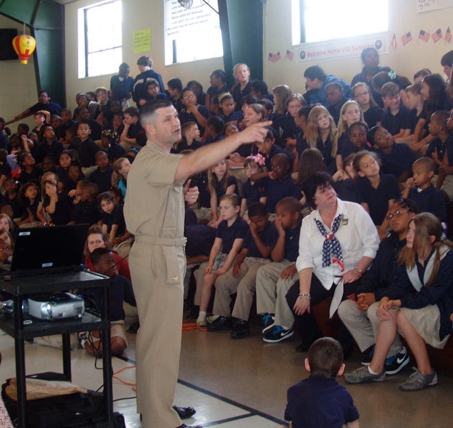 Students at G.W. Carver Primary School look on and listen as Chief Cayne Barras from the USS Sampson presents a slide show about life on a military ship and answers student’s questions.