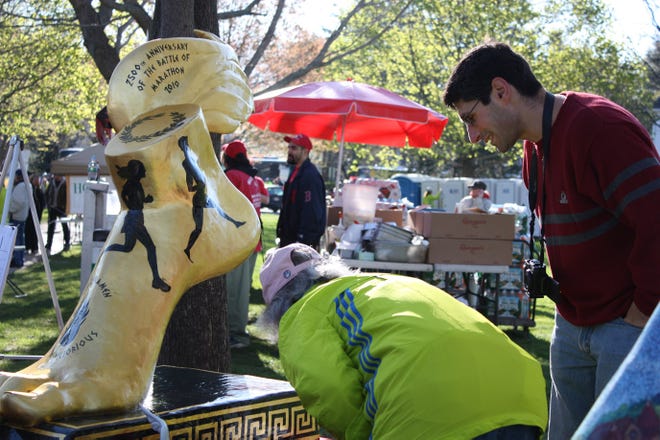 Michael Alfano of Hopkinton, who sculpted the winged foot in honor of the Boston Marathon, talks with a woman who hopes to purchase a smaller version.