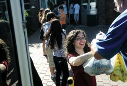 Photo by Amy Paterson/New Jersey Herald Kaitlyn Pickerelli, a senior at Hopatcong High School, hands bags of food onto the bus for Champions for Charity Tuesday morning.