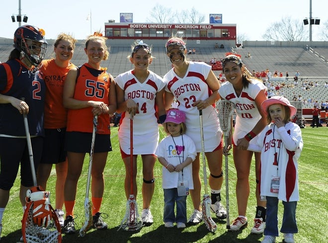 Hannah O'Brien of Weymouth, 5, far right, who is battling brain cancer, was adopted as an honorary member of the Boston University women's lacrosse team on April 3. BU players are Jenny Martin (14), Traci Landy (23) and McKinley Curro (10). Hannah's sister, Kaitlin, stands with the team.