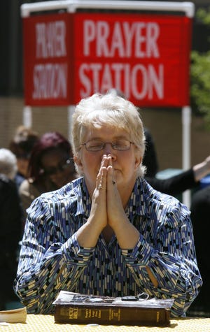 Christine Cameron pays during a gathering behind the Stark County Courthouse to celebrate the National Day of Prayer.