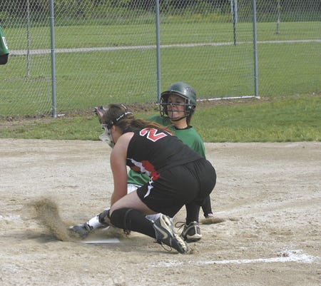 Mendon’s Lacey Cupp slides in safely to home plate while White?Pigeon pitcher Sara Anderson applies a tag.