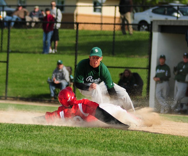 Dennis R.J. Geppert/The Holland Sentinel Holland's Aaron Doss (13) slides safely into home while Reeths-Puffer's Nick Sommerville tries to tag him out Thursday night at Holland.