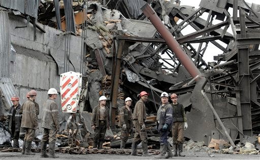Emergency workers gather near the destroyed ventilation unit at the Raspadskaya mine, hit by explosions, in the city of Mezhdurechensk in the west Siberian region of Kemerovo, Russia, Monday, May 10, 2010. Two explosions tore through the Russia's largest underground coal mine in western Siberia, over the weekend with the death toll still rising, Monday, and a rescue operation is underway for about 60 people who are still trapped underground, according to government officials.