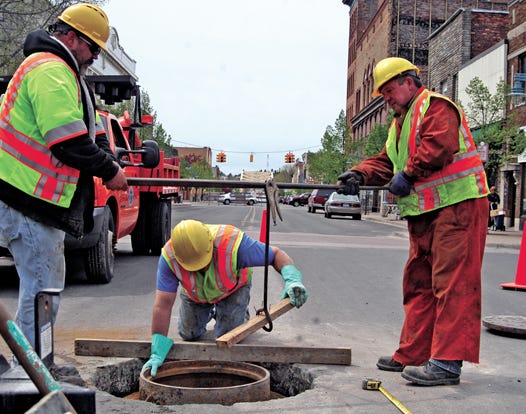 Norm Simons of St. Ignace, Kirk Mille of Engadine and Jim Litzner of St. Ignace replace a catch basin casting ring in the middle of Ashmun Street after closing down a portion of the roadway. The Michigan Department of Transportation project is targeting 26 rings including curb drains in Sault Ste. Marie