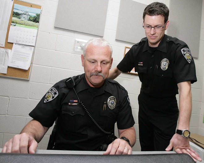Deputy Chief Brian Carbenia, standing, assists patrol officer Gary Fabynick at the computer.