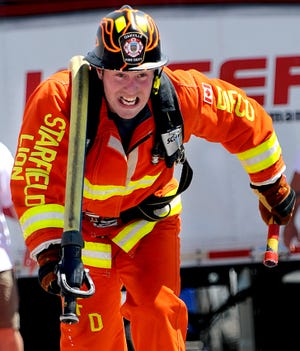 Firefighter Mark Tyler of the Oakville, Ontario fire department carries fire hose and a baton during the Firefigher Combat Challenge relay race at the Solomon Pond Mall in Marlborough Saturday.