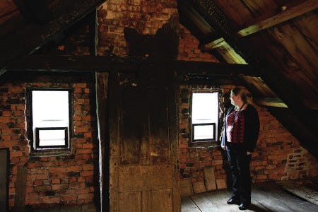 Amanda Nelson, chairperson of the Weeks House Board of Directors, looks around the attic of the c. 1710 historic Weeks Brick House in Greenland, on Friday. The house suffered some fire damage from a large barn fire in 1938.