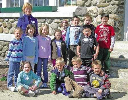 Students in Sue Hett's first-grade class pose Thursday with visiting author Tracy Kane, who helped them make fairy houses out of materials found in nature.
