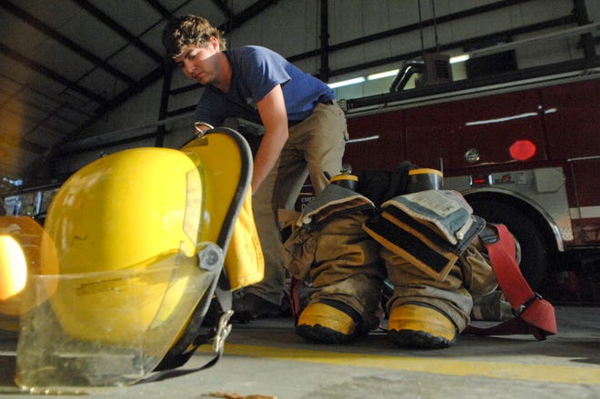 Thunderbolt firefighter Wesley Franklinslips on his airtank as he dresses for a timed fire drill during training Tuesday night at the Thunderbolt Fire Department . Richard Burkhart/Savannah Morning News