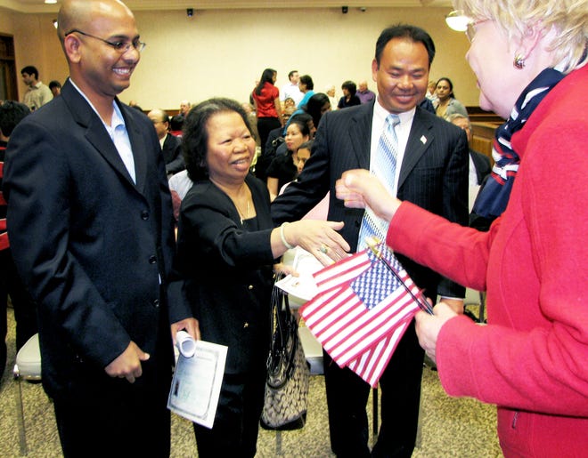 Rajesh Mishra of Dunlap, left, and Anh Nguyen of Peoria Heights accept congratulations from one of the volunteers at a naturalization ceremony Friday in Downtown Peoria. Mishra immigrated from India while Nguyen came from Vietnam to be with her son, Tuan Nguyen, right. In all, nearly 80 people took the oath of citizenship at two ceremonies at Peoria's at the U.S. District Courthouse.