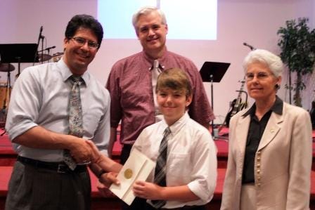 Joshua Connerty of Plymouth, a fifth grader at the New Testament School in Plymouth, with, from left, Principal Rodd Rodriguez, founding Principal Paul Jehle and teacher Lyn Haglof.