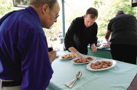 Gary Laughlin of Nashua examines a pork dish being arranged by chef Rick Korn of Rick’s at Pond View restaurant in Kingston, at the Seacoast Charter School chef competition held Sunday at Applecrest Farm Orchards in Hampton Falls.