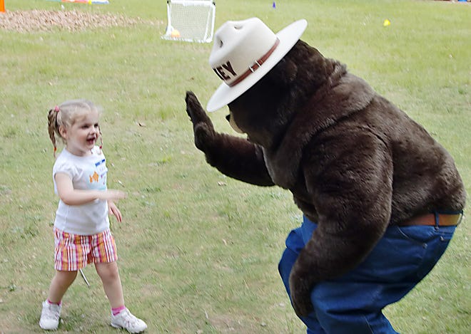 Katherine Donovan, 4, gives Smokey the Bear a high five at Watson Pond State Park Sunday.