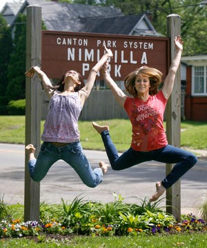 Megan Wilson, left, and Catherine Bules leap in excitement over the Canton Peace Day event they are organizing at Nimisilla Park.