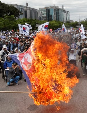 South Korean war veterans burn a North Korean flag Wednesday during a rally against North Korea in Seoul. North Korea threatened Wednesday to ban cross-border traffic and destroy South Korean propaganda loudspeakers.
