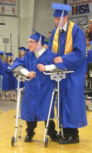 Tucker Lynn helps his twin brother, Tanner, at Friday’s graduation at PORTA. Marianne Payne/The State Journal-Register