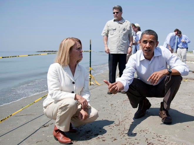President Barack Obama, left, picks up a “tar ball” as LaFourche Parish president Charlotte Randolph, center, and U.S. Coast Guard Adm. Thad Allen, national incident commander for the BP Deepwater Horizon oil spill, look on Friday in Port Fourchon, La.